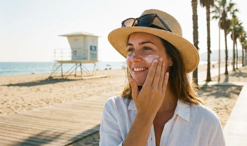 Kobieta nakładająca filtr SPF na twarz w słoneczny dzień. Kobieta nakładająca filtr SPF na twarz w słoneczny dzień.